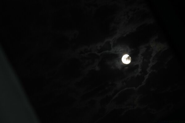 Moon in the night sky with small clouds