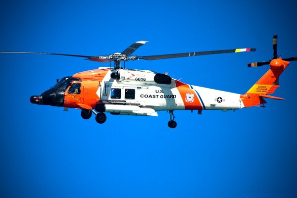 Brillante helicóptero blanco-naranja flotando en el aire