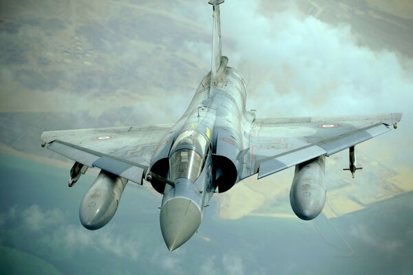 Photo of a fighter in flight against the background of fields