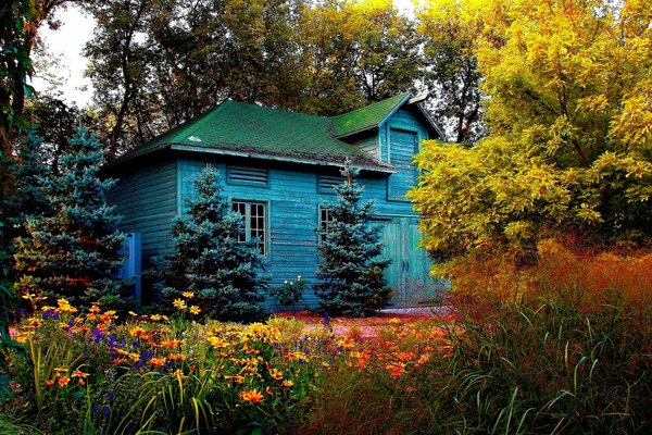 Casa azul con techo verde contra los árboles de otoño