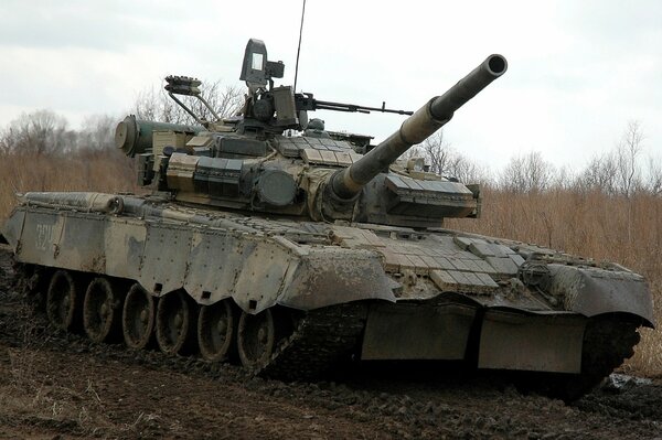 Военный танк едет по грязной дороге