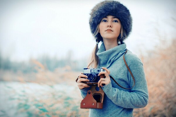 Femme dans un chapeau et avec un appareil photo dans les mains