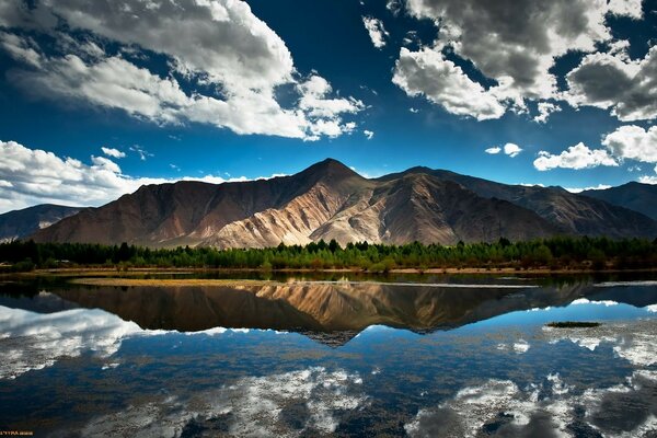 The beautiful lake reflects the mountains and the clear sky