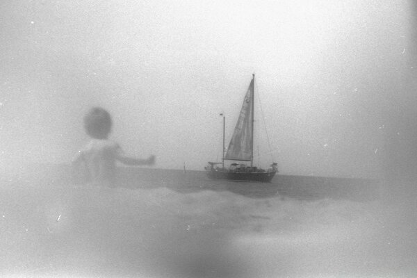 A boy meets a sailboat at sea