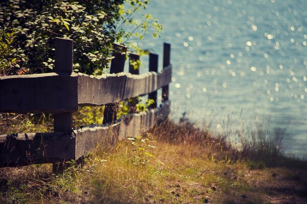 Wooden fence among grass and water in the background