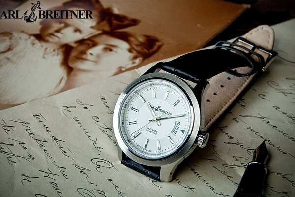 Silver watch on the background of a written letter and a vintage photo of a mother with a child