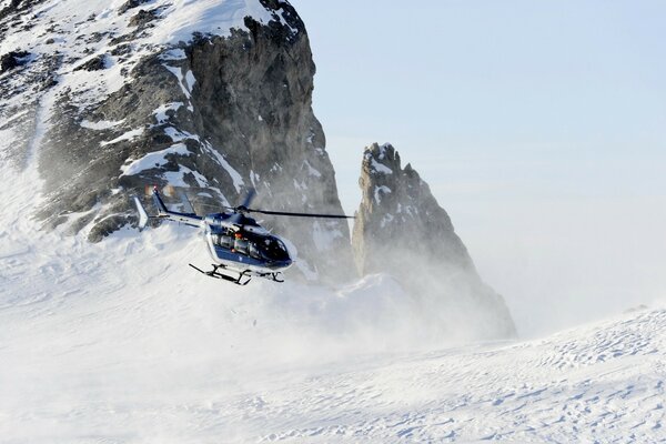 A helicopter takes off in a snow-covered mountainside