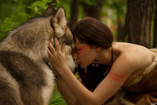 A girl hugs a wolf in the forest