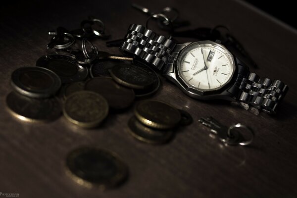 Horloge sur la table avec des pièces de monnaie et porte-clés