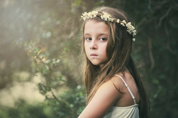 فتاة في اكليلا من الزهور البيضاء وفستان الشمس الأبيض