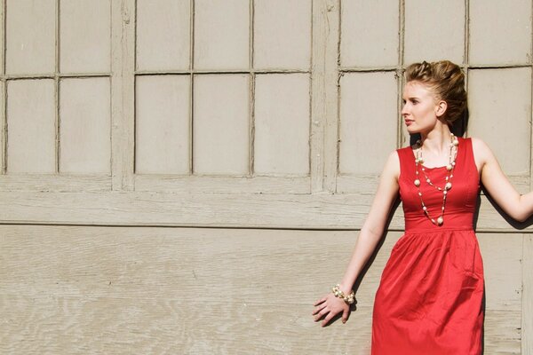 A girl in a red dress by the wall