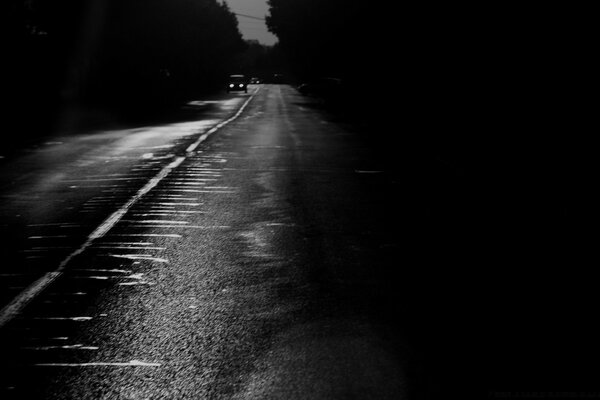 Monochrome image of a road with a car