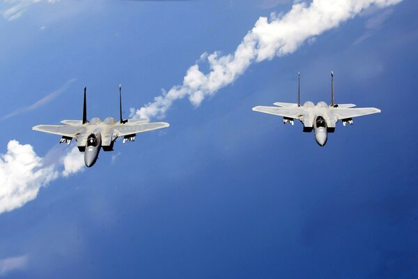 A pair of fighter jets in a blue sky the color of the sea