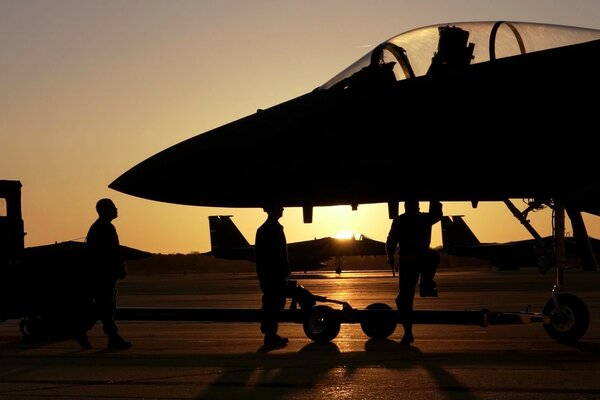 Aeródromo militar noturno com silhueta de caça