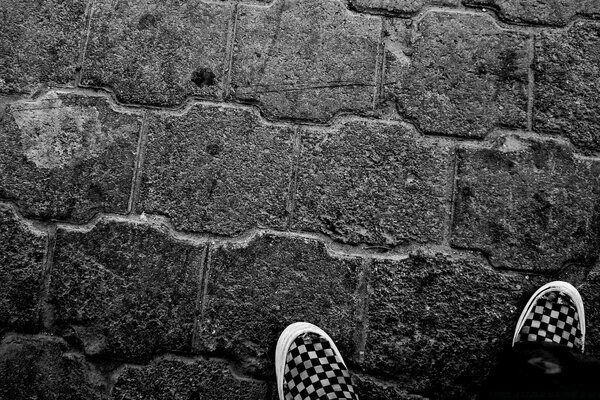 Pies en Zapatillas de deporte en una pared de piedra