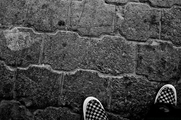 Ноги в кросівках на кам яній стіні