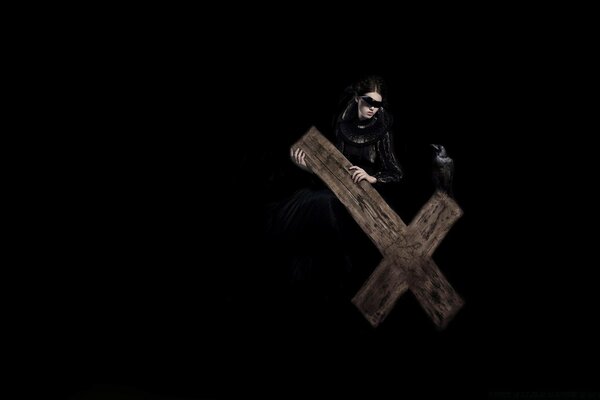 A woman in black holds a wooden cross