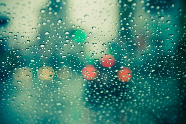 Luces multicolores a través del vidrio en las gotas de lluvia