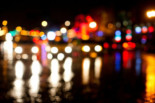 La noche borrosa multicolor de las luces reflejadas en el agua