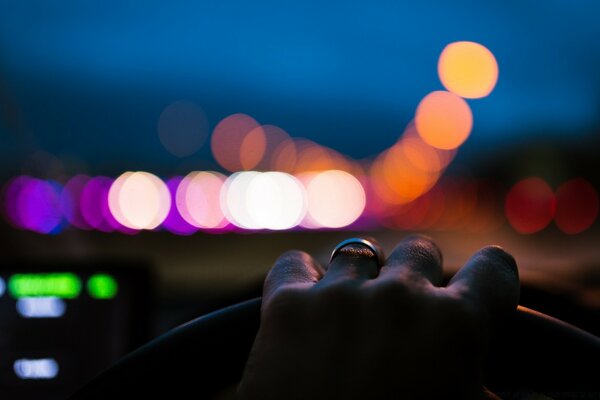 The steering wheel of the car and the hand on it and the panel