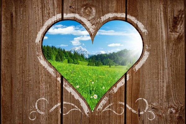 Heart-shaped hole view of a green field and forest