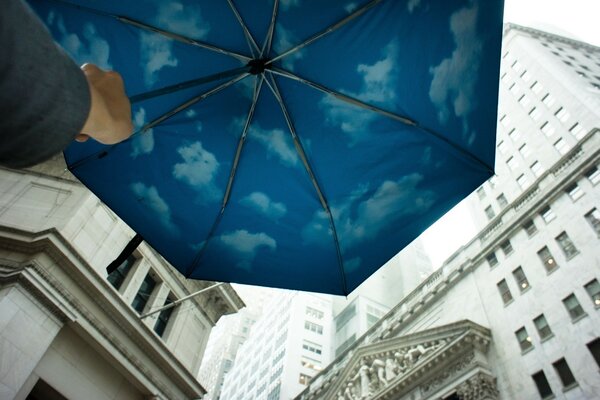 Guarda-chuva azul com nuvens perto de casas grandes