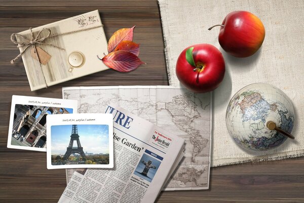 There are apples, a postcard and a newspaper on the table