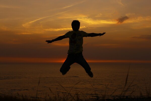 Foto von einem Sprung auf dem Hintergrund eines Sonnenuntergangs am Meer