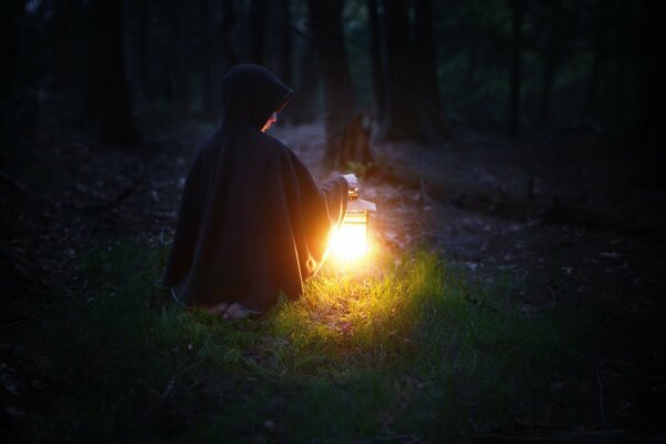 A man with a lantern at night in the forest