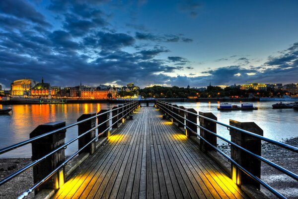 The bridge to the pier in the evening illuminated by lanterns