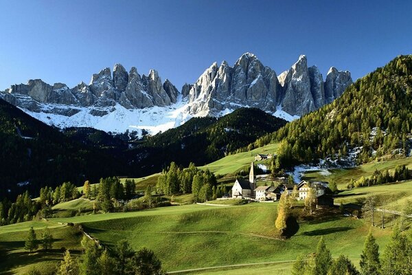 The foot of the mountain rocks trees grass village roads snow