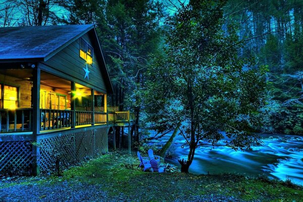 Maison dans la forêt de nuit près de la rivière