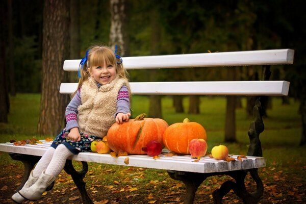 Chica en el banco con calabazas