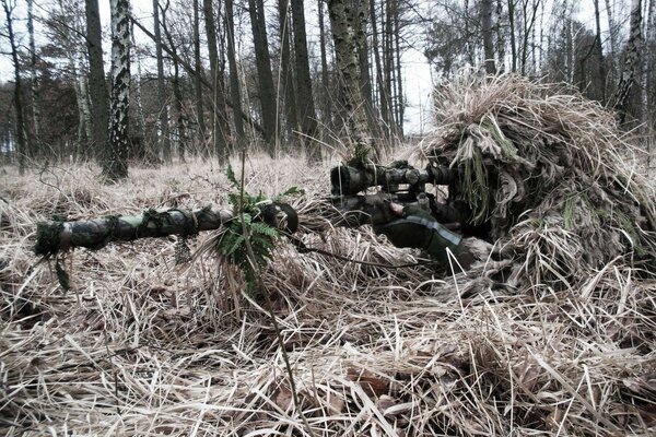 Francotirador escondido con un rifle en el bosque