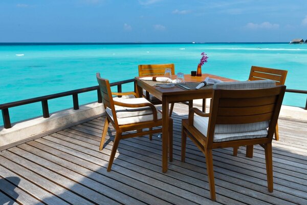 Vernada con mesa de comedor a orillas del mar azul