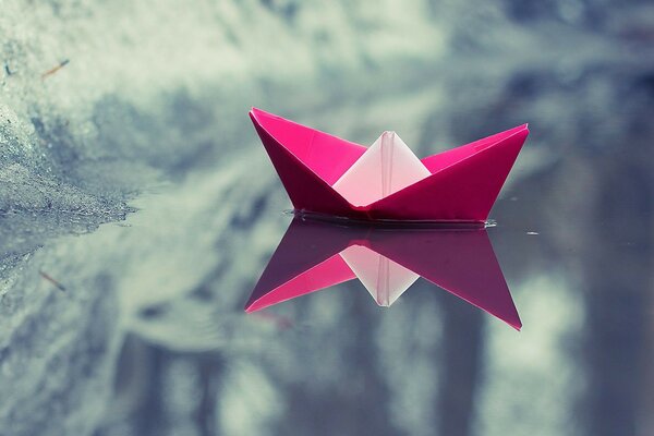 Barco de papel rosa en el agua