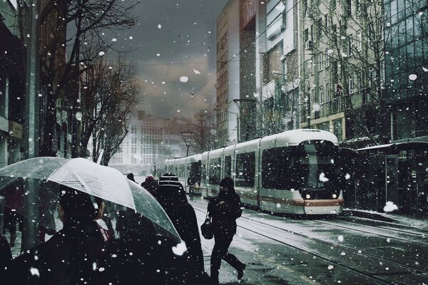 Straßenbahn und Mädchen unter plötzlichem Schnee in der Stadt