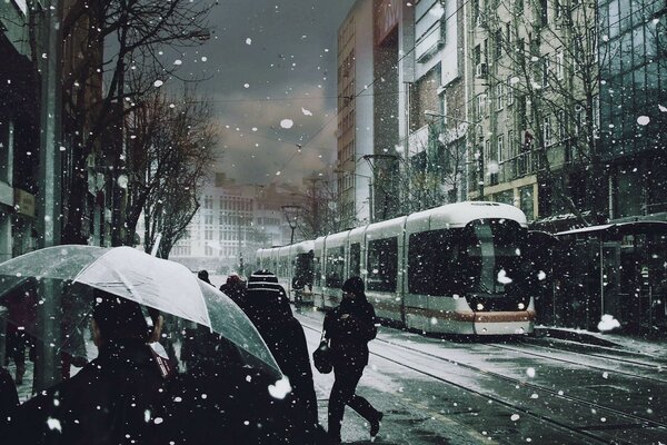 Tram and girl under sudden snow in the city