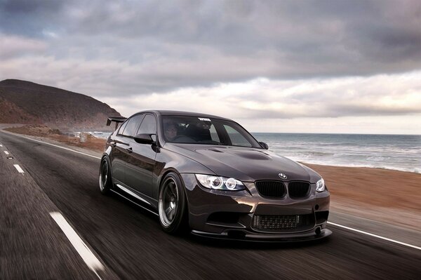 A sports car driving along the road by the sea