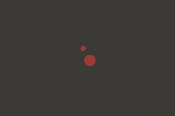 Two red dots of different diameters on a dark background