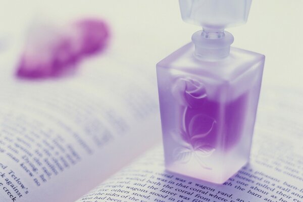 A bottle of purple perfume on an open book