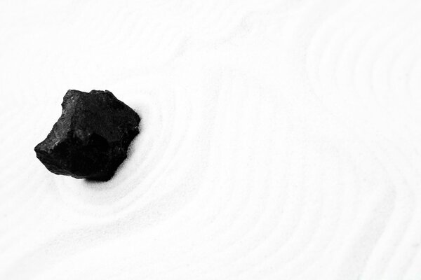 Black stone on white sand