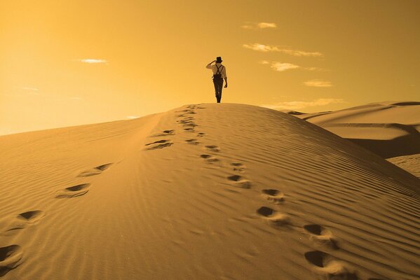 Un hombre caminando por las dunas de arena