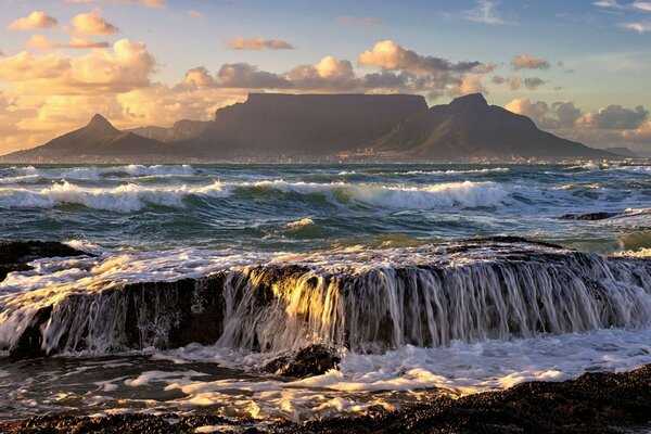 Ocean tide at sunset on the background of a mountain