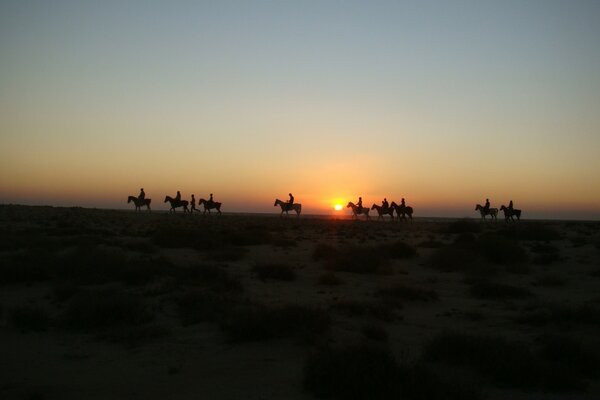 People on horseback roam in the desert