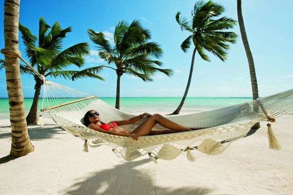 A girl is resting in a hammock on the beach