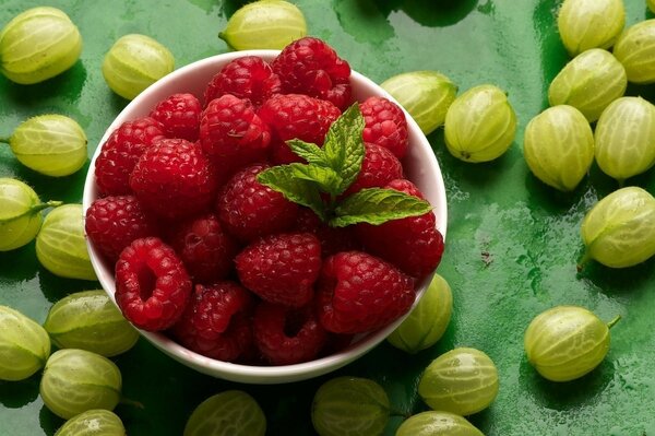 Stachelbeeren und Himbeeren auf einem grünen Tisch