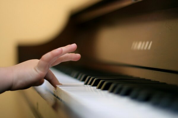 Una pequeña mano presiona las teclas del piano