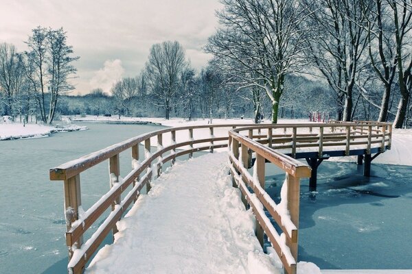 Wooden bridge on the winter pond in the park