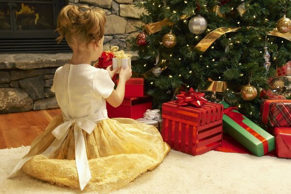 Geschenke unter dem Weihnachtsbaum. Mädchen öffnet Geschenke zu Weihnachten